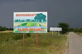 Tafel „Willkommen in Gatlukai“ auf Adygeisch am Ortseingang