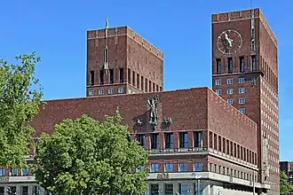 Ostturm mit Uhr, Schmuckbalustraden, Reliefplatten am Fassadenband, Bronzeskulptur eines namenlosen Herrschers, flankiert von zwei Schiffen