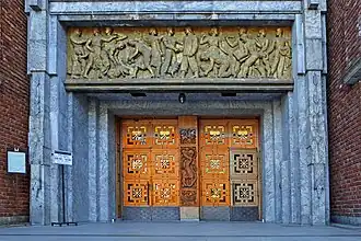 Eingangsbereich mit geschnitzten Türen und einem Fries als Tympanon