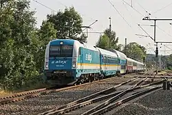 Der Zug wird gezogen von einer weiß-grünblau-orangegelb lackierten Elektrolokomotive, an zweiter Stelle hinter der Lokomotive befindet sich ein Doppelstockwagen, die Wagen sind unterschiedlich lackiert, fünf von ihnen tragen eine der Lokomotive ähnliche Lackierung