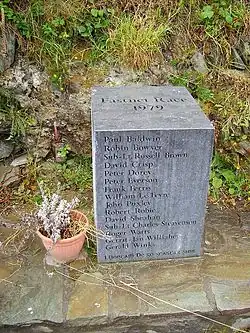 Das Bild zeigt einen schlichten qubischen Stein mit den Namen der 15 Opfer