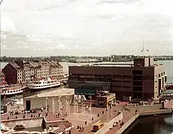 Die Fotografie zeigt ein großes quaderförmiges Gebäude an einem Hafen.