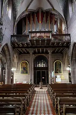 Mittig vom Kirchenschiff aufgenommenes Foto des Eingangsportals mit der Empore und der dort stehenden Orgel