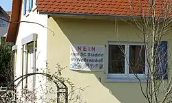 Protestplakat gegen den Bau des SC-Stadions im Wolfswinkel an einem Haus in der Mooswaldsiedlung