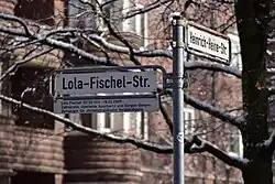 Straßenschild mit Legendentafel an der Lola-Fischel-Straße Ecke Heinrich-Heine-Straße in Hannover-Südstadt: „Lola Fischel (07.03.1914 - 18.03.2009) Zahnärztin, überlebte Auschwitz und Bergen-Belsen. Zeitzeugin für christlich-jüdische Verständigung.“