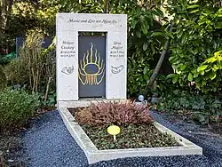 Grabstein Holger Czukay (links) und Ursa Major (rechts). In der Mitte ein Symbol, oben drüber steht "Music and Love are Miracles"