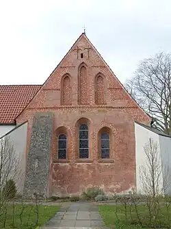 Chorgiebel, oben back­stein­sich­tig, unter den Fenstern Backstein aufgemalt