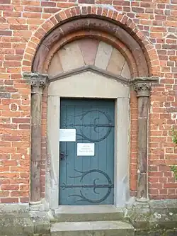 Westportal, mittelalterliche Farb­fassung vom Tym­pan­on und Rund­stab­bogen, ersetz­ter Tür­rahmen