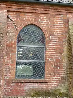 Westlichstes Joch der Nord­wand: links oben neben dem neu­goti­schen Fenster ein halb vom neu­zeit­lichen Strebe­pfeiler verdeckter gotischer Fenster­bogen aus roten und schwarz glasierten Form­steinen