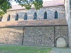 Langhaus von Süden: Portal und Obergaden spitzbogig mit Quader­mauer­werk, Kreuz­gang­an­schluss rund­bogig mit Feldsteinmauerwerk