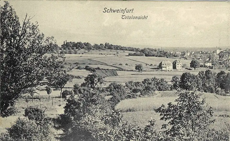 Blick von der Haardt über die Breite Wiese zum Steinberg in den 1920er Jahren. Mit drei Häusern im Mittelgrund (von links nach rechts): Lindenbrunnenweg Nr. 12/10, Nr. 8 und (rechts vom Baum) Deutschhöfer Straße Nr. 30. Dahinter die Klingenhöhe (Felder), dahinter ein Taleinschnitt (Klingenbrunnstraße) und dahinter der Teilberg (Bäume am Horizont, heute Hofrat-Graetz-Straße). Hinten rechts das Tal des Marienbachs mit dem östlichen Stadtrand