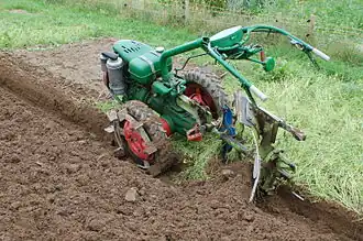Einachstraktor bei der Pflugarbeit mit einem Drehpflug, Aufsteckgreifer an den Rädern für bessere Traktion