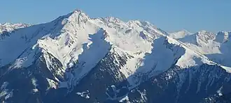 Der Bergstock der Ahornspitze: Links der Mitte der Nord- und Südgipfel, links davon der Ostgrat, rechts der Westgrat (Poppbergschneid) mit Übergang zu Toreggenkopf, Filzenschneid und Filzenkogel, ganz rechts vorn das Ahornplateau (Filzenboden) mit Bergstation der Ahornbahn und weiteren Liftanlagen, vor dem Gipfel rechts das Fellenbergkar mit Edelhütte sowie Hochleger, Mittelleger und Niederleger der Alpenrosenalm, vor dem Gipfel das Kar Steinkarl mit der Ahornachalm, im Hintergrund Rosswandspitze, Vordere und Hintere Stangespitze, Wollbachspitze und Grüne-Wand-Spitze