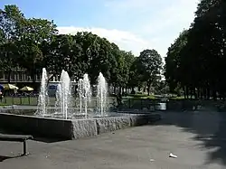 Foto eines Springbrunnens mit mehreren Fontänen in einem Park