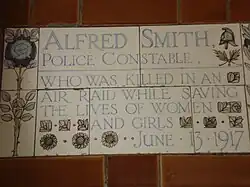 A tablet formed of five tiles of varying sizes, bordered by yellow and blue flowers in an art nouveau style