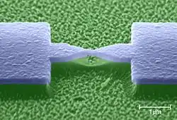 Fertige Nanobrücke aus Aluminium auf der Polyimid-Unterlage, betrachtet im REM (künstlich eingefärbt).