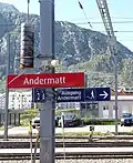 Rotes Bahnhofsschild der Matterhorn-Gotthard-Bahn in Andermatt, Schriftart FF Dax