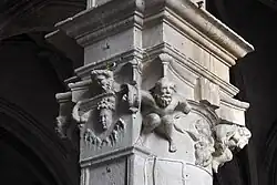 Kapitell mit Köpfen und männlichen Figuren