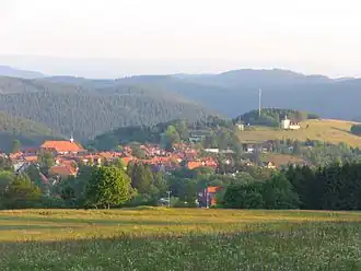 Blick vom Südhang der Jordanshöhe (723 m) südostwärts über Sankt Andreasberg mit Martini-Kirche (links) hinweg zum Glockenberg (mittig bis rechts) mit dortigem Glockenturm; im Hintergrund rechts die Koboltstaler Köpfe (ca. 673 m)