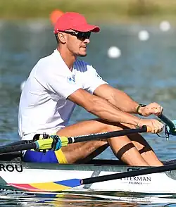 Cornea trägt ein weißes Trikot, eine blaue Hose und eine rote Mütze.