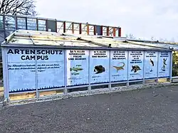 Außenaufnahme des Artenschutzcampus im Allwetterzoo Münster. Glasbau mit Informationsfolien beklebt.