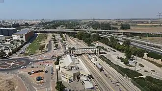 Luftbild 2020 mit Bahnhof Aschdod – ʿAd Ha­lom (vorn), Anschlussstelle gleichen Na­mens, BIG Fashion vor Busdepot und Park ʿAd Halom (obere Mitte rechts) am Nachal Lachisch