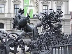 Gitter, im Hintergrund die Brunnenfigur Brunnenbach