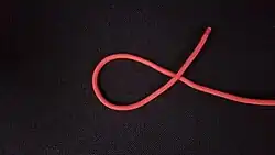 Man legt mit dem rechten Ende (hier rot) von rechts nach links ein Rechtsgängiges Auge. Das heißt, das lose Ende (hier rot) wird entgegen dem Uhrzeigersinn über das Seil gelegt.