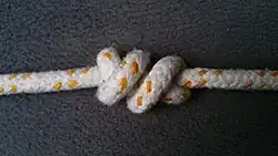 Den Knoten an beiden Tampen (Enden) festziehen und dabei die äußeren Törns nach innen drücken.