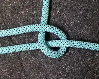 Hier derselbe Halbe Schlag um eine Leine (kann auch die eigene sein) gebunden. Würde man die innenliegende Leine aus dem Halben Schlag herausziehen, erhielte man ein Auge.