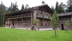 „Essglocke“ als Dach-/Glockenreiter: Überdachte Astgabel mit Glocke auf einem Bauernhof im Salzburger Land