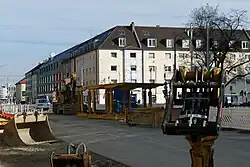 Baustelle mit verschiedenen Baumaterialien vor Stadthäusern an einer Kreuzung