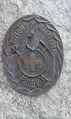 Das Originalabzeichen in Bronze (70 × 55&nbsp;cm) der diplomierten Bergführer des Schweizer Bergführerverbands (S.B.V.) auf dem Bergführerdenkmal in St.&nbsp;Niklaus Dorf
