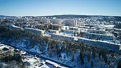 Drohnenbild eines Stadtviertel auf einer Anhöhe mit mehreren Reihen- und Hochhäusern