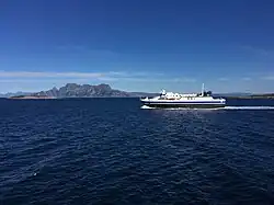Foto einer fahrenden Fähre auf dem Meer, im Hintergrund Berge