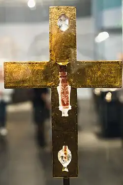 Rückseite des Goldkreuzes, umlaufender Schriftzug und andere Ornamenten drei Stellen, an denen die Bergkristalle eingelassen sind, scheint von der Vorderseite das Licht durch