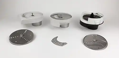 Schnitzelwerk offen. V.&nbsp;l.&nbsp;n.&nbsp;r.: Raffelscheibe / Trägerscheibe in einem Stück, Gussmetall-­Trägerscheibe mit sichelförmigen Scheibeneinsätzen, Kunststoff­trägerscheibe mit runder Raffelscheibe