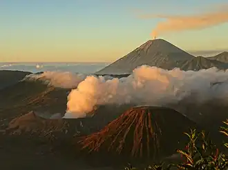 Bromo (rauchender Krater links) mit Batok (rechts vorne), im Hintergrund der Vulkan Semeru.
