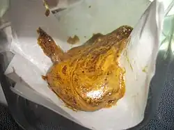 Ein Bild, welches das Ergebnis einer Extraktion von Cannabisbestandteilen mittels Butan zeigt. Die Farbe ist gold-braun.