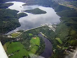 Rurtalsperre Schwammenauel (Blickrichtung Westen) mit Staudamm (Vordergrund Mitte), Halbinseln am Tonsberg (linke Bildmitte) und Eschauel (hinten rechts) sowie Insel Eichert (Bildmitte)