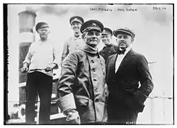 Schwarz-weiß-Foto mit fünf Personen vor einem Schiffsschornstein. Zwei sind nachträglich mit Namen beschriftet.