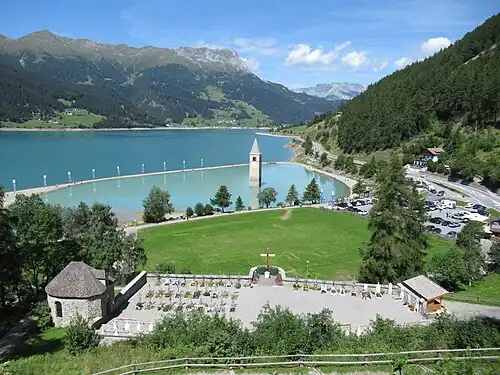 Blick von der Annakapelle auf den Friedhof Graun, den Kirchturm der alten Pfarrkirche St. Katharina und den Reschensee