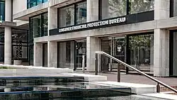 Betongebäude mit großen Glasfenstern und Türen. Über dem Eingang steht in weißen Versalien "Consumer Financial Protection Bureau"