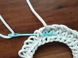 …wobei die Nadel immer von rechts nach links unter den Schlingen­schnitt­stellen hindurch geführt wird; für Rechtshänder mag es zweckmäßig sein, spiegel­verkehrt zu arbeiten.