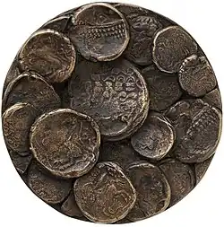 Rückseite einer Bronzemedaille mit keltischen Münzen in vergrößerter Darstellung, die sich detailreich und plastisch übereinander- und nebeneinanderlegen, erzeugen ein geschichtetes Relief.