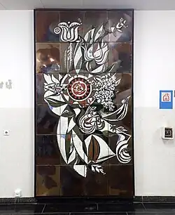 Dunkelbraunes Emaille-Wandrelief mit einer roten stilisierten Blüte mittig und zahlreichen weißen stilisierten Blüten drumherum