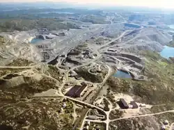Luftbild einer von Kiesgruben, Straßen und Seen geprägten Landschaft, im Vordergrund ein Industriegebäude
