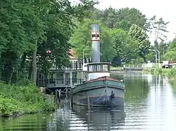 Schleppdampfer im Schleusen-Oberwasser: links die Werft, im Hintergrund die ehemaligen Schleusen