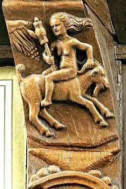 Nackte Frau reitet verkehrt herum auf einem „(alten) Bock“