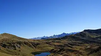 In der Bildmitte das Sünser Joch (1903&nbsp;m&nbsp;ü.&nbsp;A.) an der Gemeindegrenze zwischen Dornbirn und Damüls. Links der Hübsche Bühel 2032&nbsp;m&nbsp;ü.&nbsp;A.), rechts das Portlahorn (2010 m.ü.A.). In der Mitte unten, der Sünsersee, dahinter die Damülser Berge.